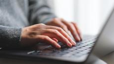 Hands typing on a laptop computer