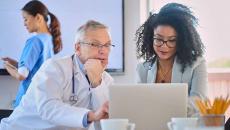 Doctor and businessperson looking at laptop screen