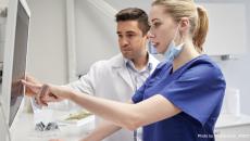 Healthcare worker pointing to a screen with another in the background