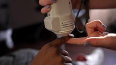 Hands use a Medtronic device on a patient's hand to aid in testing pulse oximetry quality