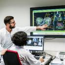 Healthcare worker pointing at medical image on a display to coworkers