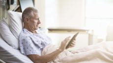 Patient using tablet in hospital bed