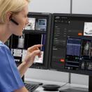 Healthcare worker with eapiece looking at medical images on a computer screen