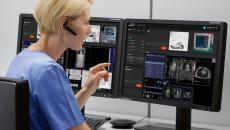 Healthcare worker with eapiece looking at medical images on a computer screen