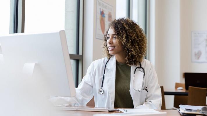 Doctor at a desktop computer looks at ease completing administrative burdens.