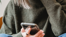 Mobile phone in the hands of a person in green sweater